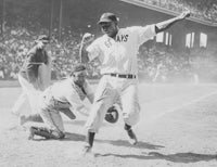 a black and white photo of a baseball player running to home plate